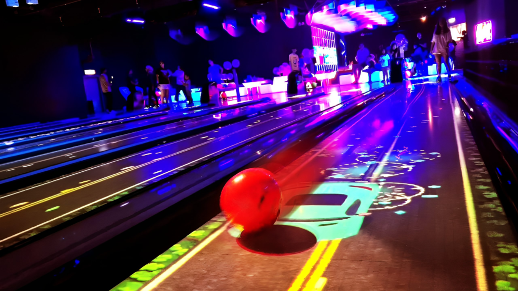 Bowling ball rolling alongside an interactive car on bowling lanes, showcasing IQHDA Interactive's innovative gaming experience