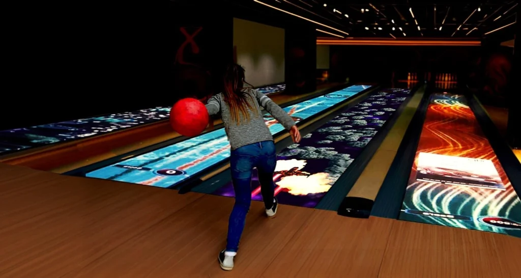 A girl throwing a bowling ball on immersive interactive bowling lanes, with vibrant visuals displayed on the lane