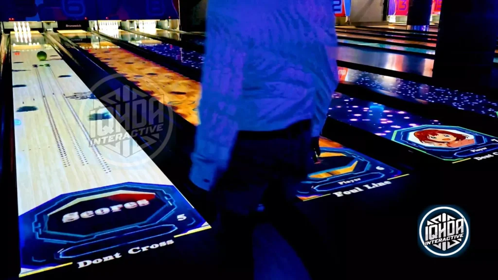 Player bowling on IQHDA Interactive AR lanes featuring realistic score lane, cartoon avatars, and cosmic visual effects